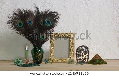 Vase of Peacock Feathers With Green Jewelry and Gold Photo Frame