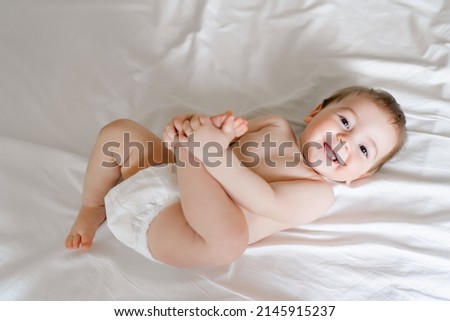 happy joyful baby in diapers lying on white bed. High quality photo Royalty-Free Stock Photo #2145915237