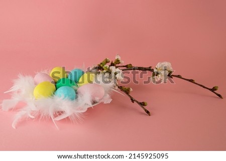 Happy Easter! Easter card with a picture of a nest of colored eggs on a pink background decorated with blooming branch