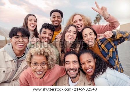 Many beautiful people standing in a circle smile at the camera taking a portrait outdoors - Large group of multiracial friends taking a selfie - Happy young students taking a photo outside school