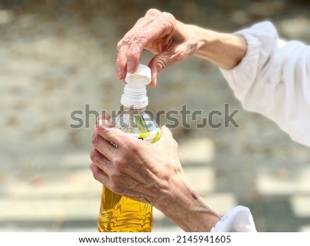 Hands of an elderly woman who closes the lid of a plastic bottle