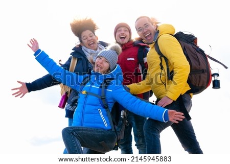 Cheerful group of hiker friends taking a selfie with arms in the air on top of the mountain - Hiking or trekking concept - white background - selective focus
