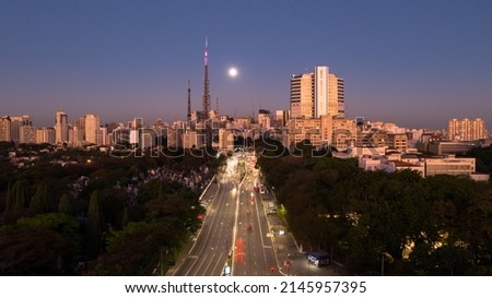Aerial image in long exposure of Avenida Doutor Arnaldo during dusk with full moon rising behind the buildings. Sao Paulo