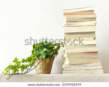 Many books and foliage plants piled up in white wall background