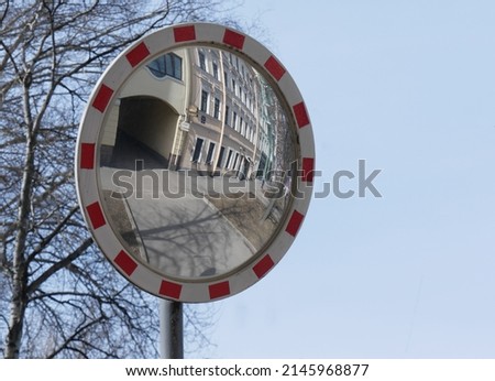 Abstract reflection of urban landscape in round frame with signal coloring. Architecture of old Petersburg. Road spherical safety mirror on background of the sky and trees. Focus on background
