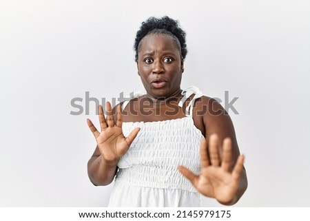 Young african woman standing over white isolated background moving away hands palms showing refusal and denial with afraid and disgusting expression. stop and forbidden. 
