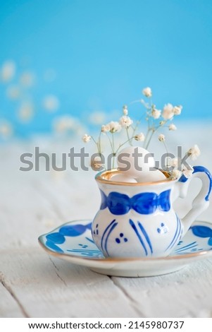 Vintage cup with easter eggs on white wooden table and blue background