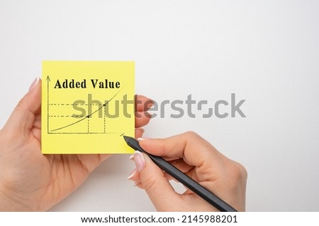 Closeup on businesswoman holding a card with ADDED VALUE rising arrow and chart, business concept image