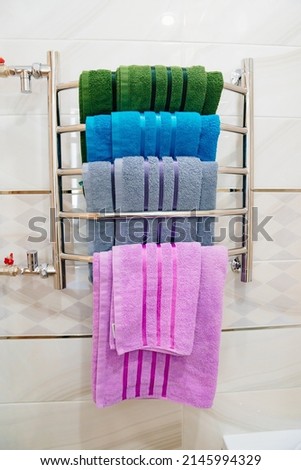 heated towel rail with multi-coloured towels. storage and drying of towels in the bathroom. Royalty-Free Stock Photo #2145994329