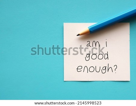 On copy space blue background, pen and note AM I GOOD ENOUGH? - negative self talk showing self doubt, inner voice with critical judgement - feeling not good enough Royalty-Free Stock Photo #2145998523