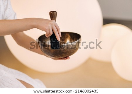 Close-up of a Tibetan singing bowl in your hands - Translation of mantras: transform your impure body, speech and mind into a pure exalted body, speech and mind of a Buddha. Royalty-Free Stock Photo #2146002435