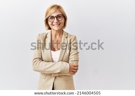 Middle age blonde business woman standing over isolated background happy face smiling with crossed arms looking at the camera. positive person. 