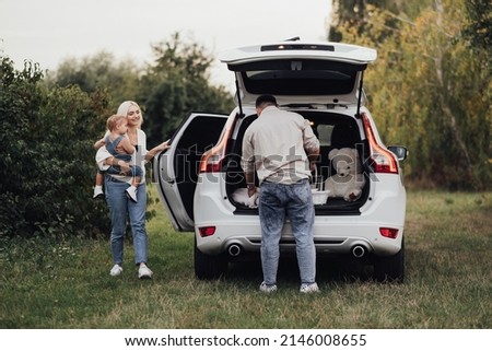 Two Parents with Their Little Kid Preparing to Picnic Time Outdoors, Young Family Enjoying Road Trip on SUV Car Royalty-Free Stock Photo #2146008655