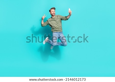 Full length profile photo of crazy blogger man jump hold telephone make selfie wear pullover isolated blue color background