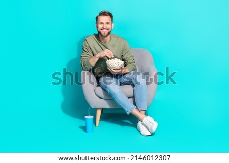Full body photo of millennial blond guy watch tv eat wear sweater jeans footwear isolated on turquoise background
