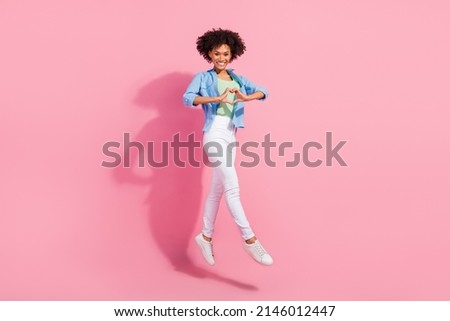 Photo of affectionate lady jump fingers demonstrate heart symbol wear denim shirt trousers sneakers isolated pink color background