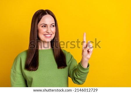 Portrait of attractive cheerful woman touching press device copy space isolated over bright yellow color background