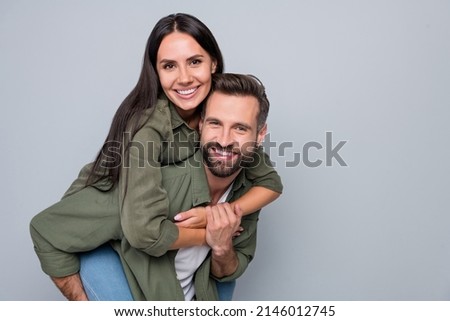 Portrait of attractive cheerful couple friends hugging having fun piggy backing weekend isolated over grey pastel color background