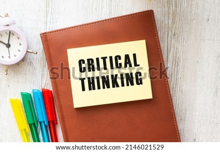 Notepad with text CRITICAL THINKING on a white background, near laptop, calculator and office supplies. Business concept.