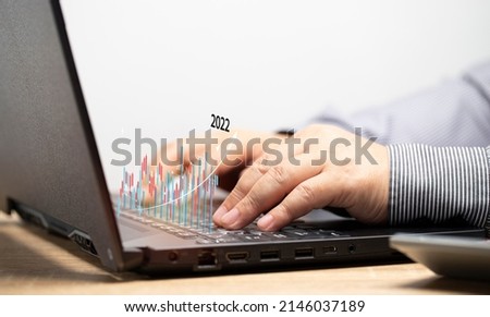 Businessmen conduct online stock trading transactions by his notebook. The stock chart is in an uptrend. Make trading decisions through viewing bar chart data.