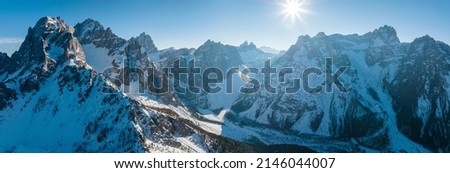Idyllic view of sun shining on kronplatz mountain range against blue sky. Panoramic view of shadow over snow covered landscape. Idyllic view of alps during sunny day in winter.