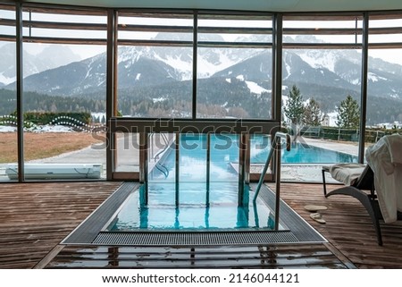 Way towards swimming pool in resort. Snowcapped mountains seen from glass window. Scenic view of alps in background during winter.