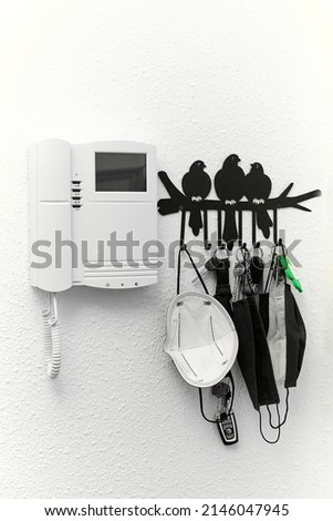 White anti-coronavirus FP 2 masks, hung together with several keys and next to the door intercom in a private house, ready to use.