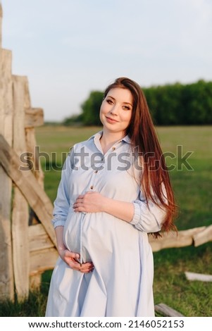 Pregnant girl in summer outdoors in the setting sun 