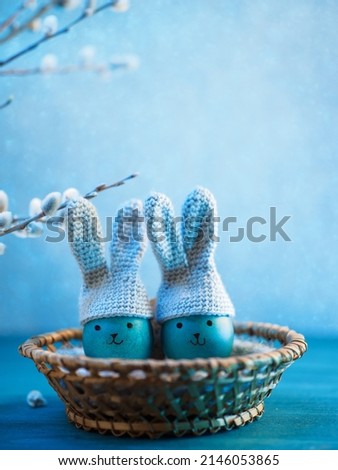 Creative Happy Easter greeting card. Painted blue eggs in knitted hats with bunny ears. Vertical photo copy space