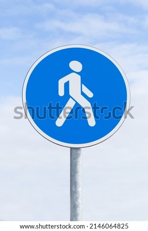 Pedestrians Path. Blue round road sign under cloudy sky, close up vertical photo