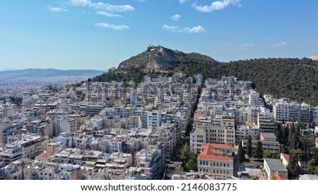 Aerial drone photo of urban cityscape and iconic chapel of Saint George on top of Lycabettus hill with beautiful deep blue sky, Athens, Attica, Greece