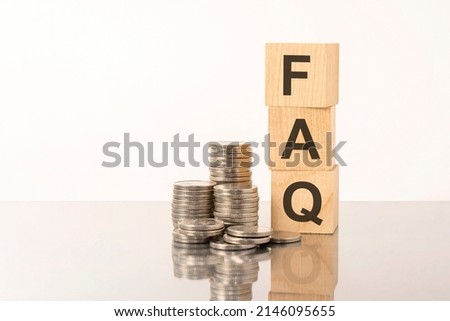 the word FAQ is laid out of wooden cubes with letters on white background with coins. FAQ - short for Frequency Asked Questions
