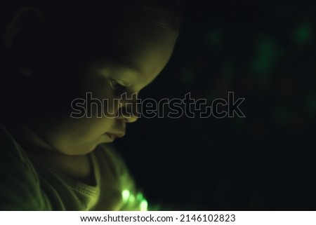 Closeup portrait of a caucasian little boy playing with colorful night light lamp before going to bed. High quality photo