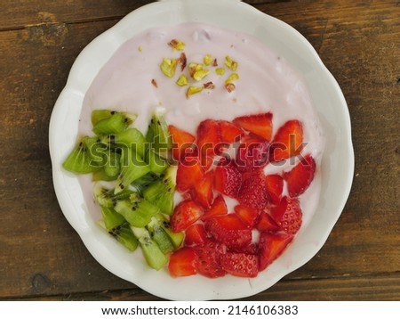 Selective focus of Fruit breakfast and blueberry yoghurt plate. Strawberry, kiwi, and greek yogurt. Healthy food concept on brown wooden background, top angle view