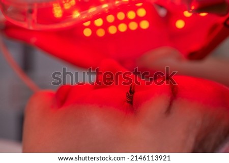 LED light anti-aging mask for facial skin care in a spa slow motion. A woman lies on a couch in a special mask. Modern technologies of beauty and health. Royalty-Free Stock Photo #2146113921