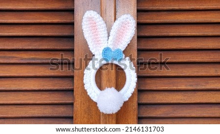 A cute crochet white bunny garland on the wooden door.
