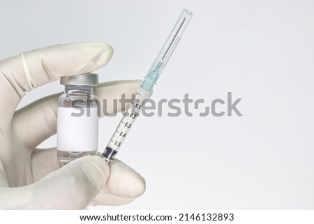 Left hand withe medical gloves holding vial and syringe on a white background. Medical concept.