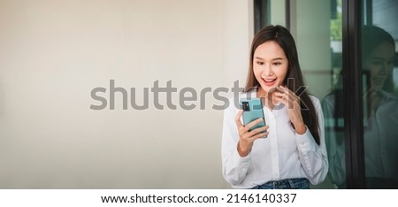 Asian woman standing and using smartphone search for information, shoping online, talking video call show a happy expression. Royalty-Free Stock Photo #2146140337