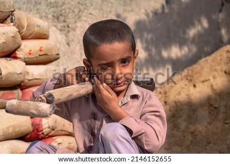 child boy sitting holding a shovel on a construction site