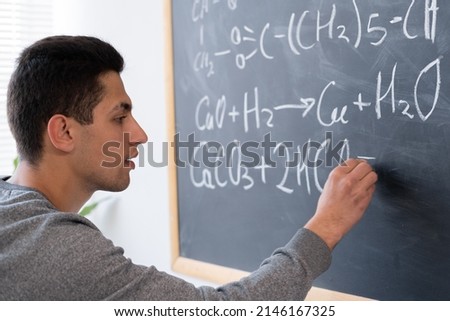 Arabic student at university chemistry lesson writing formulas on blackboard, education and science chemistry, organic science concept