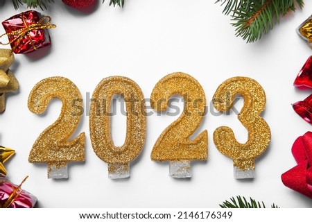 Happy New Year 2023 greeting card. Candle numbers on white background and layout of Christmas tree, balls, gifts. Close up and copy space, Selective focus.