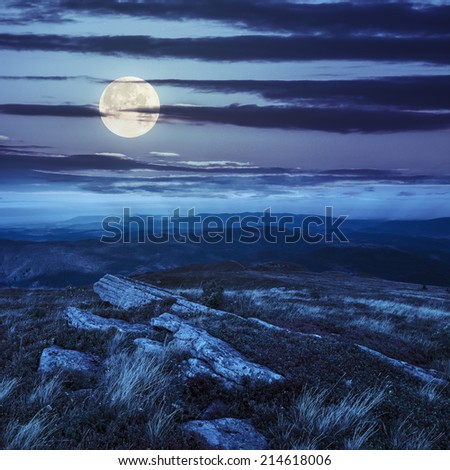 white sharp stones on the hillside on top of mountain range at night in full moon light