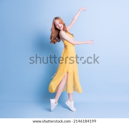 Full length image of young Asian woman wearing yellow dress on blue background Royalty-Free Stock Photo #2146184199