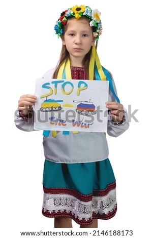 A little Ukrainian girl with tearful eyes holds a drawing with the inscription "Stop the war" in her hands. A child in Ukrainian national clothes. Studio photo on a white background.