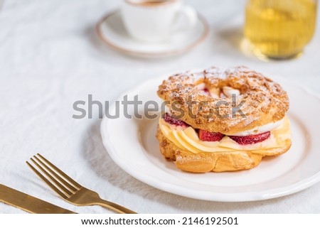 Traditional French Dessert called Paris Brest on a light grey background with powder sugar and strawberries