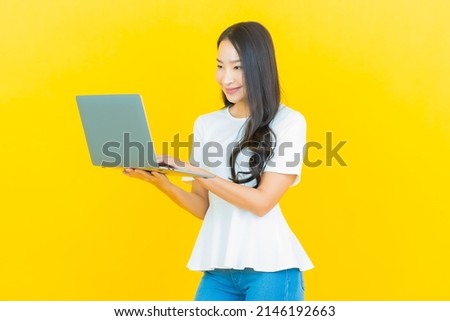 Portrait beautiful young asian woman smile with computer laptop on yellow isolated background
