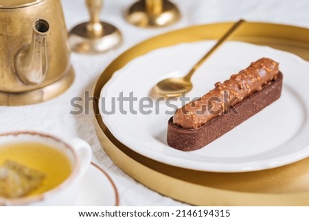Chocolate cake bar with hazelnut on top with cup of tea