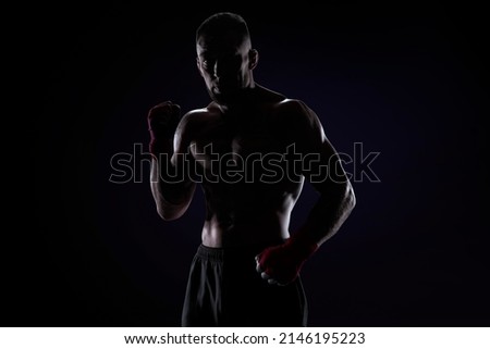Kickboxer in red bandages posing on a blue background. The concept of mixed martial arts. MMA