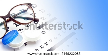 Contact lenses case and eye glasses on and eye test chart. Vision concept. Way to improve vision Royalty-Free Stock Photo #2146232083
