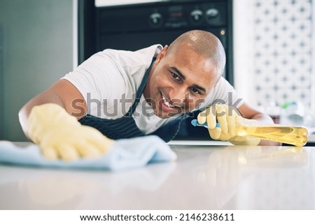This counter needs to be squeaky clean. Shot of a young man wiping a surface at home. Royalty-Free Stock Photo #2146238611